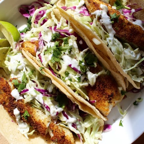 Grilled Fish Tacos topped with fresh cilantro and red onion, served with lime wedges on a rustic wooden board.