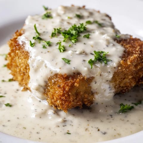 Golden-brown Chicken Fried Steak drizzled with creamy white gravy and chopped parsley.