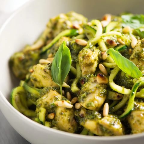 Pesto zucchini chicken bowl featuring sautéed chicken breast, crisp zucchini noodles, and a drizzle of lemony pesto for a fresh Mediterranean meal.  
