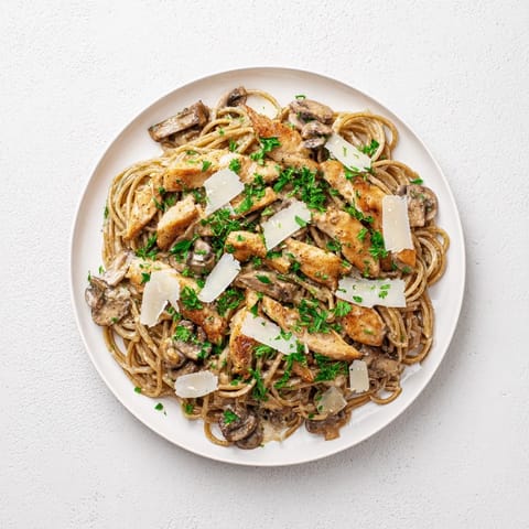 A serving of Creamy Mushroom Chicken Spaghettini twirled on a fork, highlighting the velvety mushroom sauce and spinach.  
