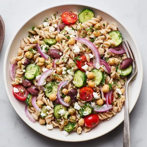 A chilled serving of Lemon Herb Chickpea Pasta Salad, tossed with fresh dill and topped with feta.