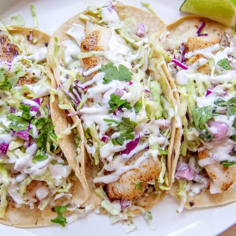 Fresh Fish Tacos with golden-brown fillets, shredded cabbage, and a drizzle of creamy sauce for a coastal-inspired meal.