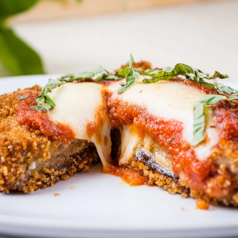 Fresh basil garnishes a steaming slice of homemade Eggplant Parmesan served alongside a crisp green salad for dinner.