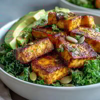 Tofu breakfast bowl with avocado and kale, golden tofu cubes, sautéed greens, and creamy avocado slices in a nourishing vegan meal.  