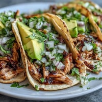 Tender slow cooker salsa verde chicken tacos ready for vibrant toppings like avocado and lime.